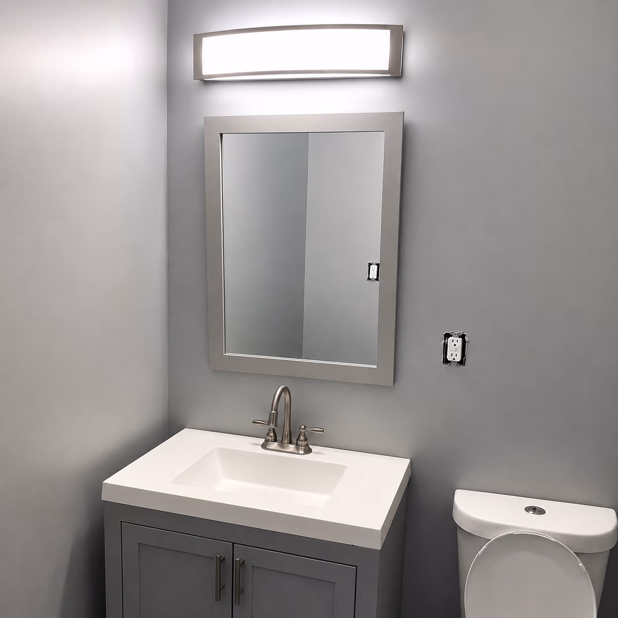 Modern bathroom with gray walls, vanity with sink, mirror, light fixture, and toilet with open lid.
